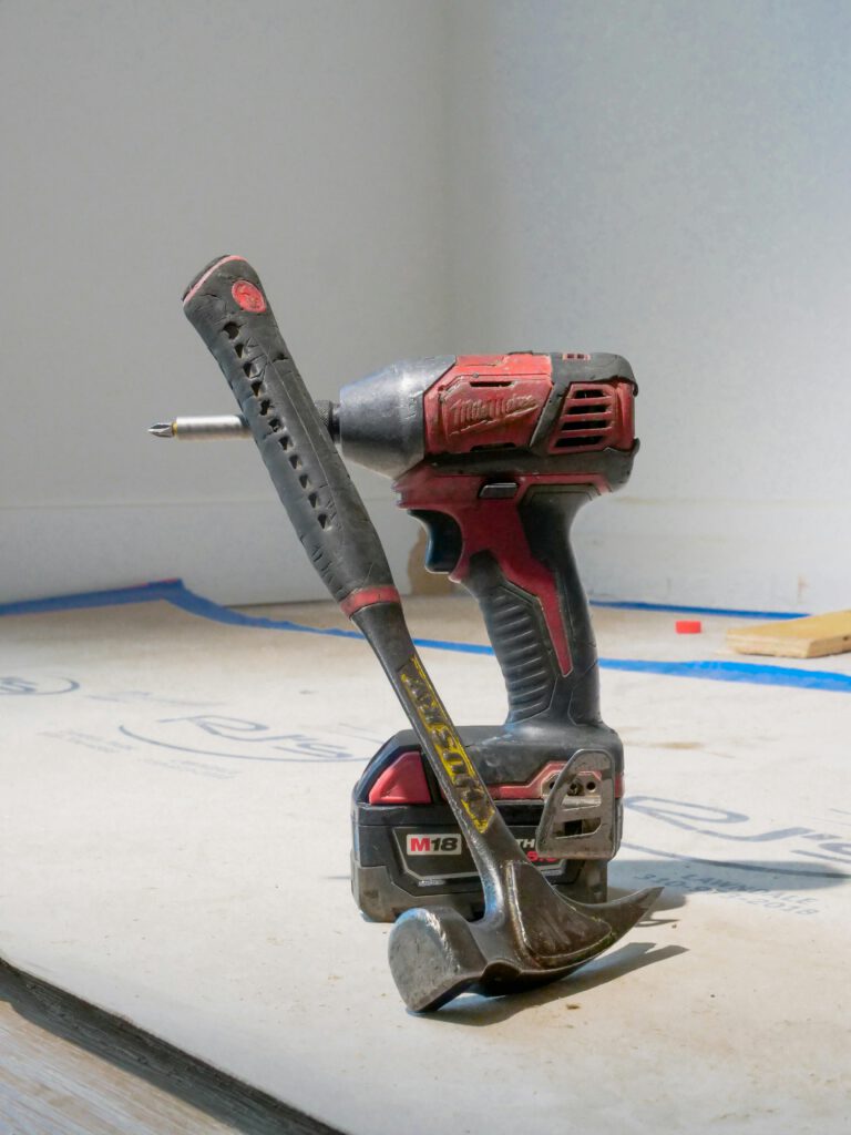 hammer leaning on electric drill on the floor